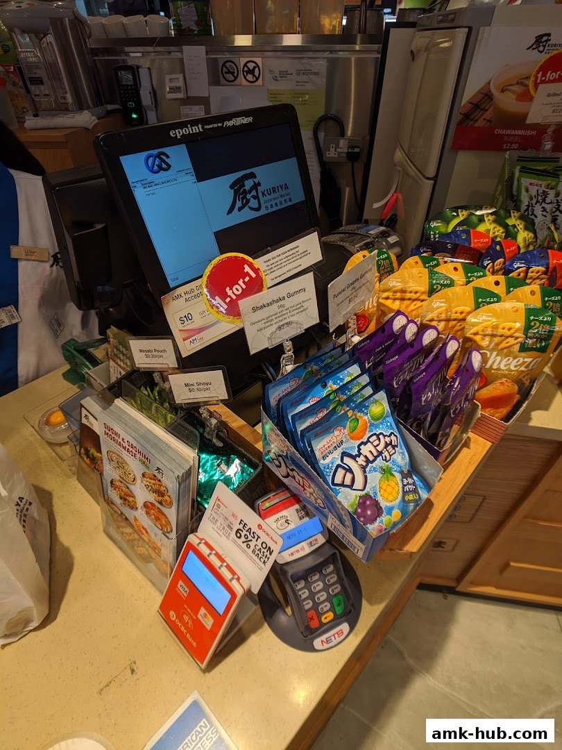 A checkout counter at Kuriya Japanese Market with various snacks and payment terminals.