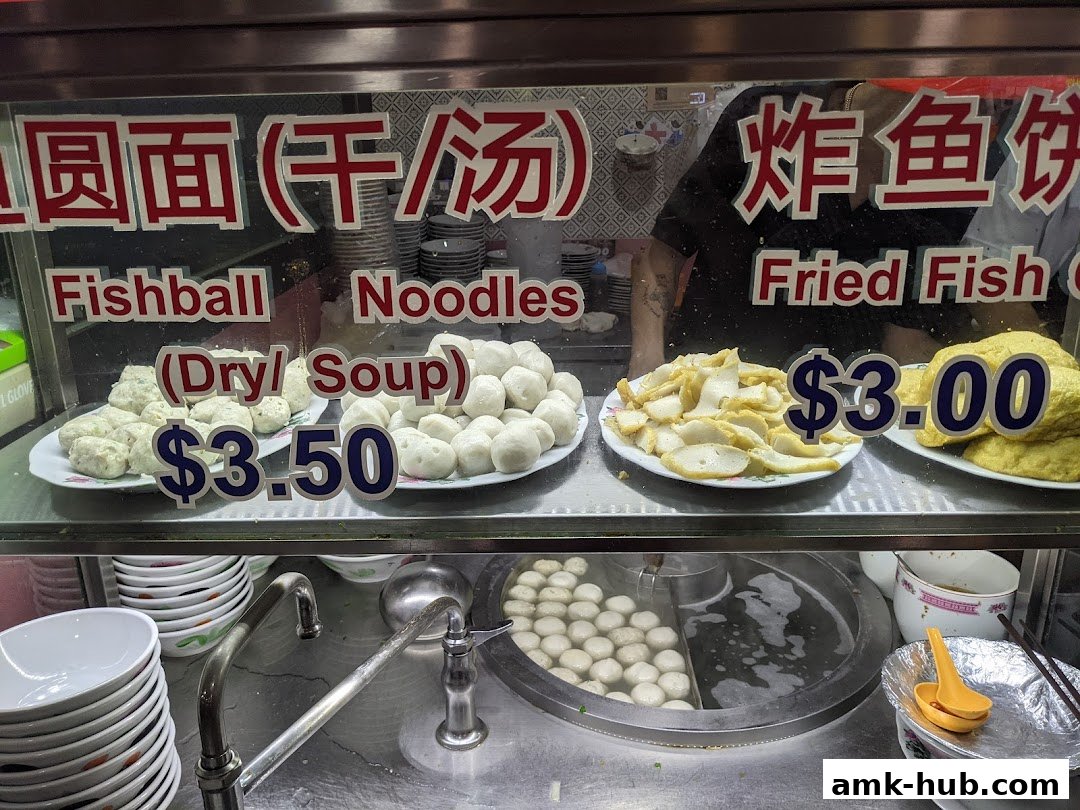 A display of fishball noodles and fried fish cakes with prices.