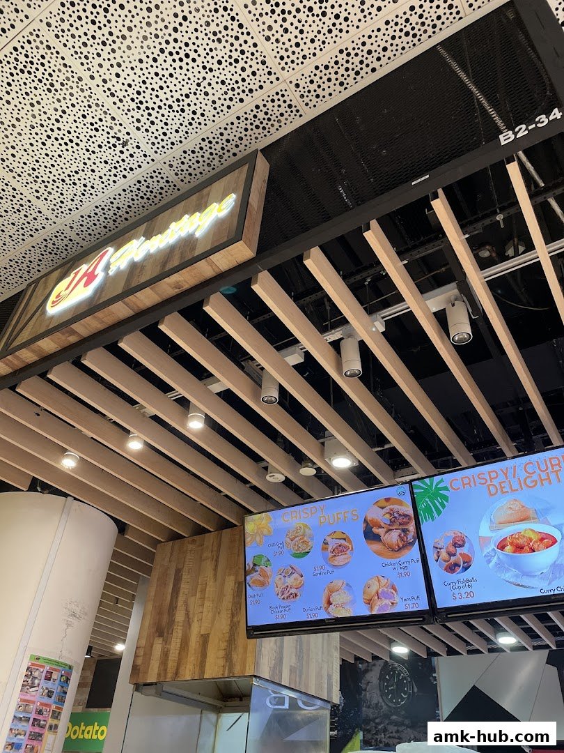 A shop front with a lit sign and a digital menu displaying crispy puffs and curry delights.