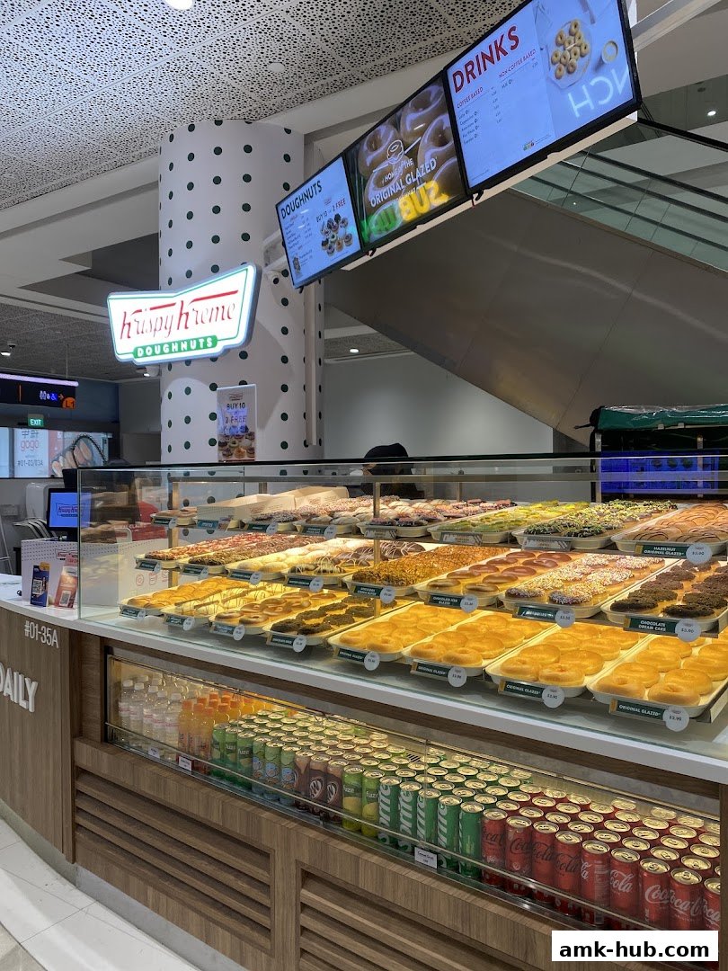 A display case filled with a variety of Krispy Kreme doughnuts and drinks.