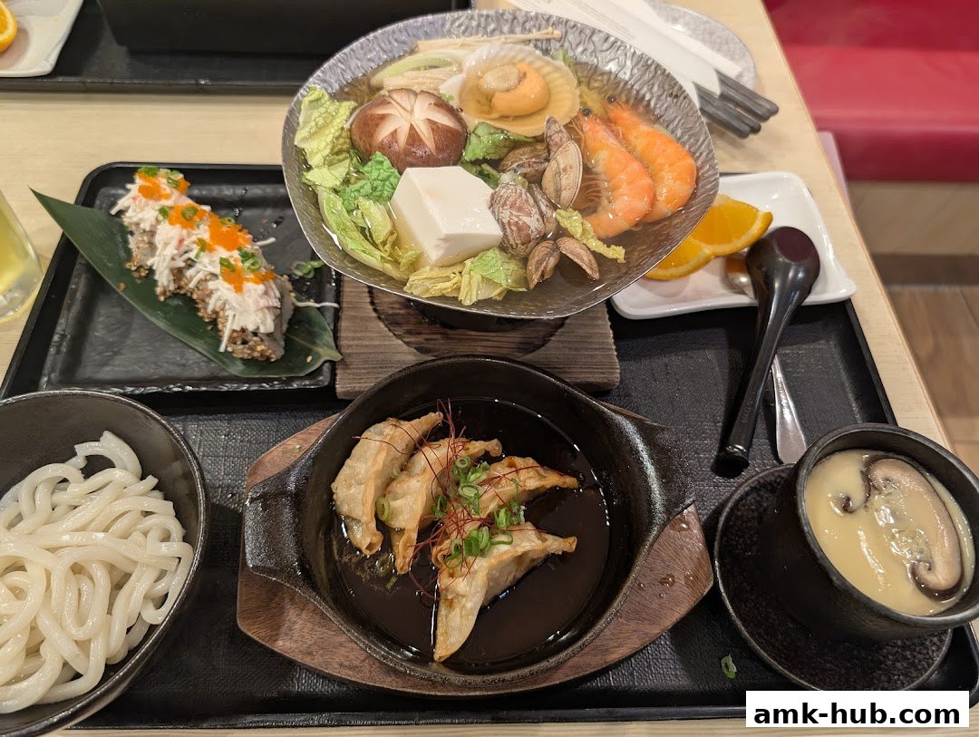 A spread of Japanese dishes including sushi, hot pot, udon noodles, gyoza, and chawanmushi.