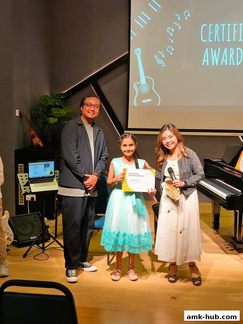 A girl receives a certificate from two adults at a music award ceremony.