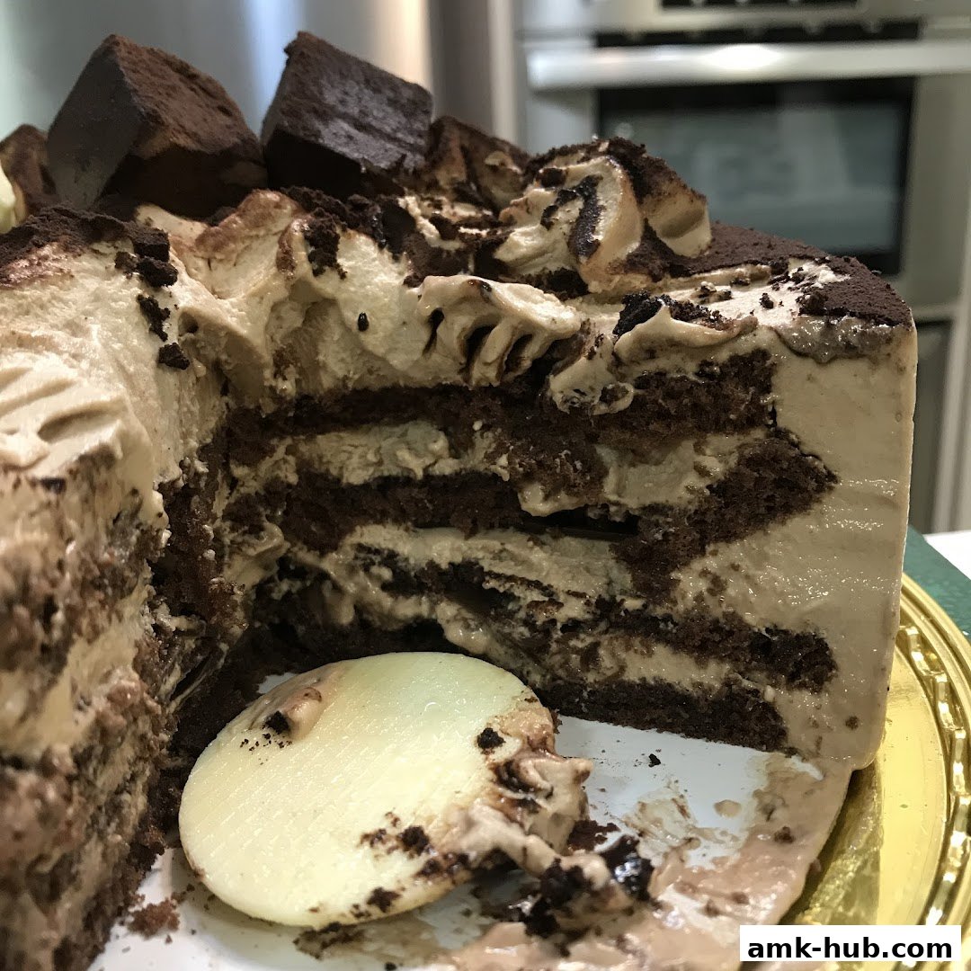 A slice of rich chocolate cake with layers of cream and chocolate chunks.
