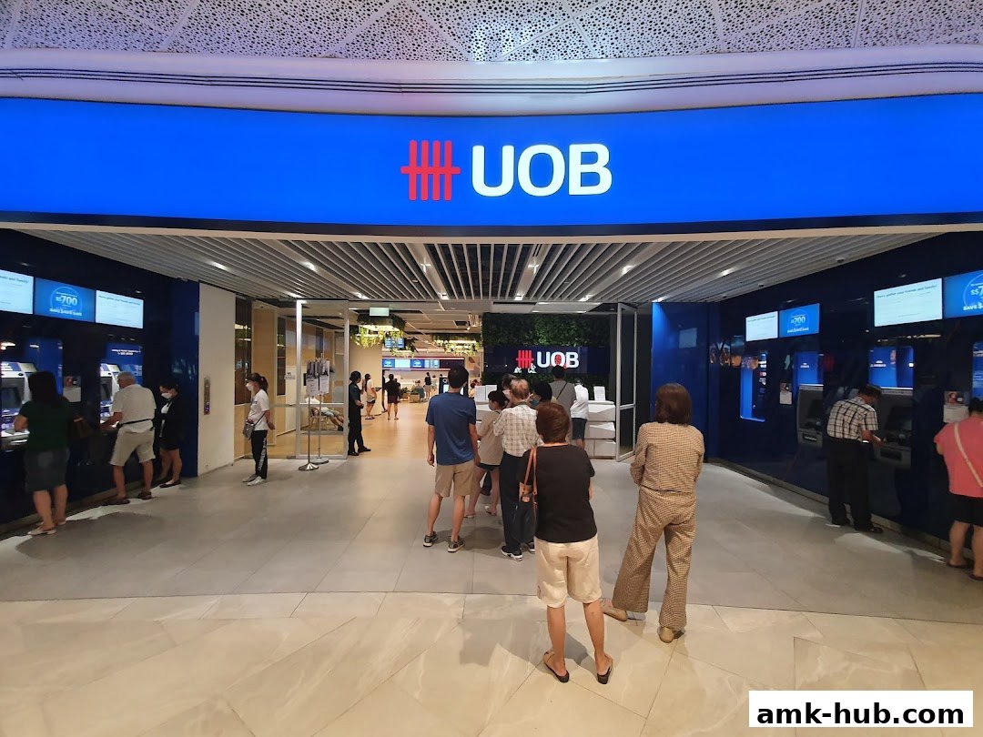 People queue at the UOB Wealth Banking Centre entrance with ATMs visible.