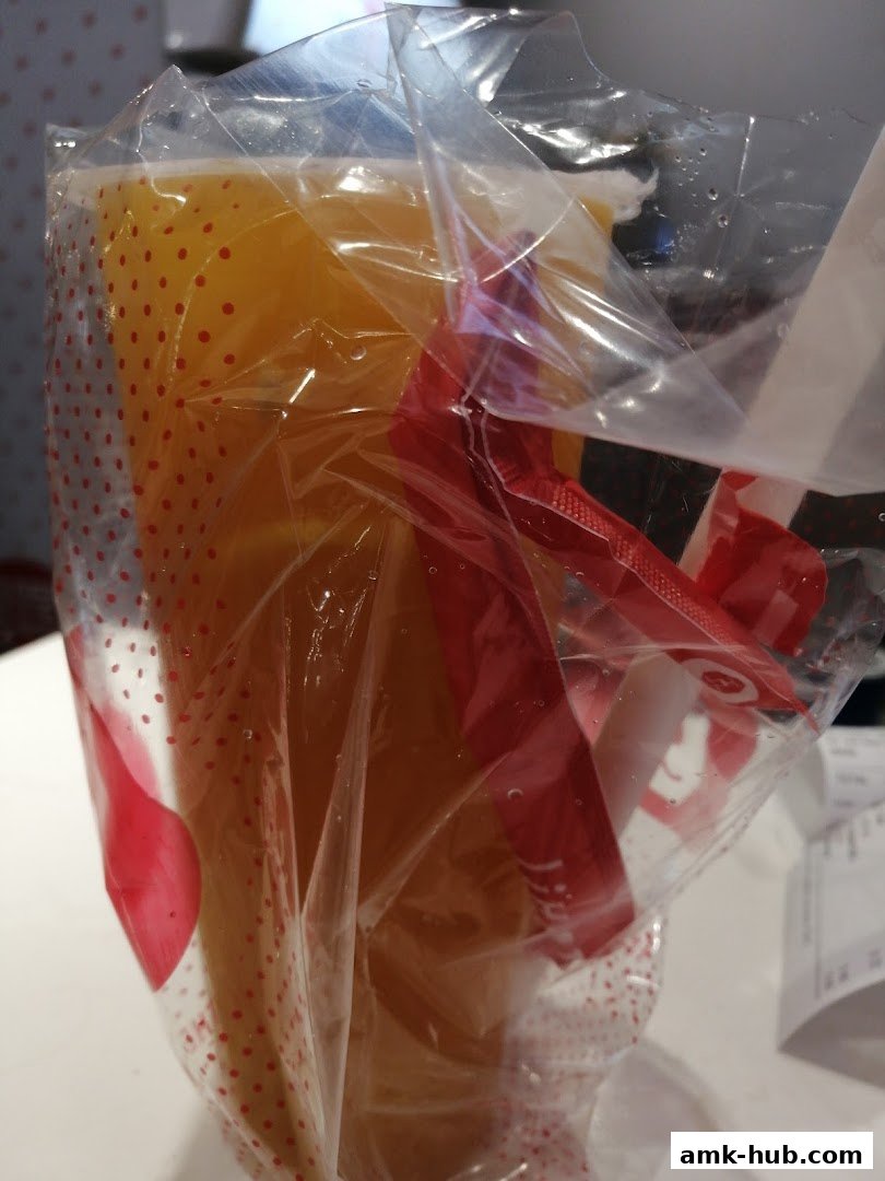 A close-up of a plastic-wrapped beverage with a red ribbon and polka dot pattern.