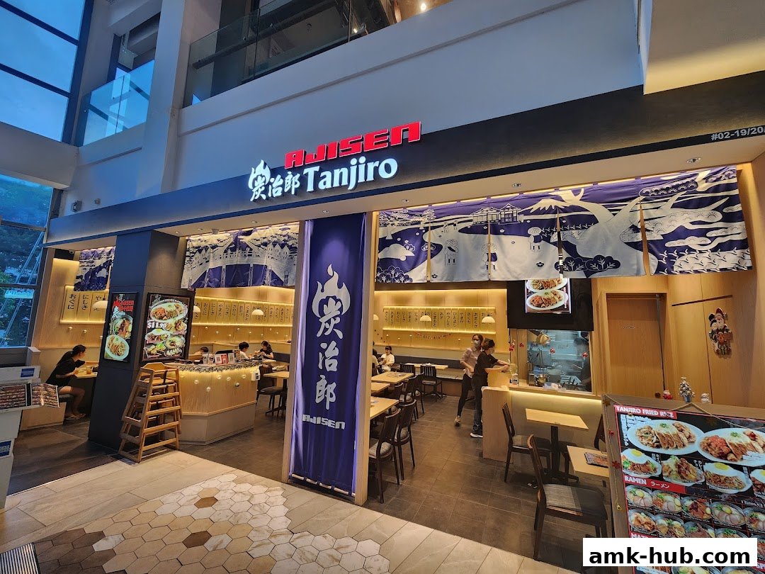 The exterior of a Japanese restaurant called Ajisen Tanjiro, with customers inside and a menu display.