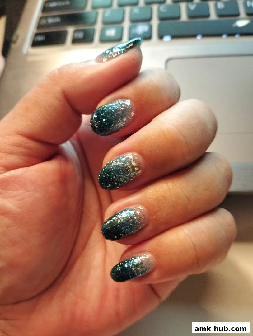 A hand with beautifully manicured nails featuring a glitter ombre design.
