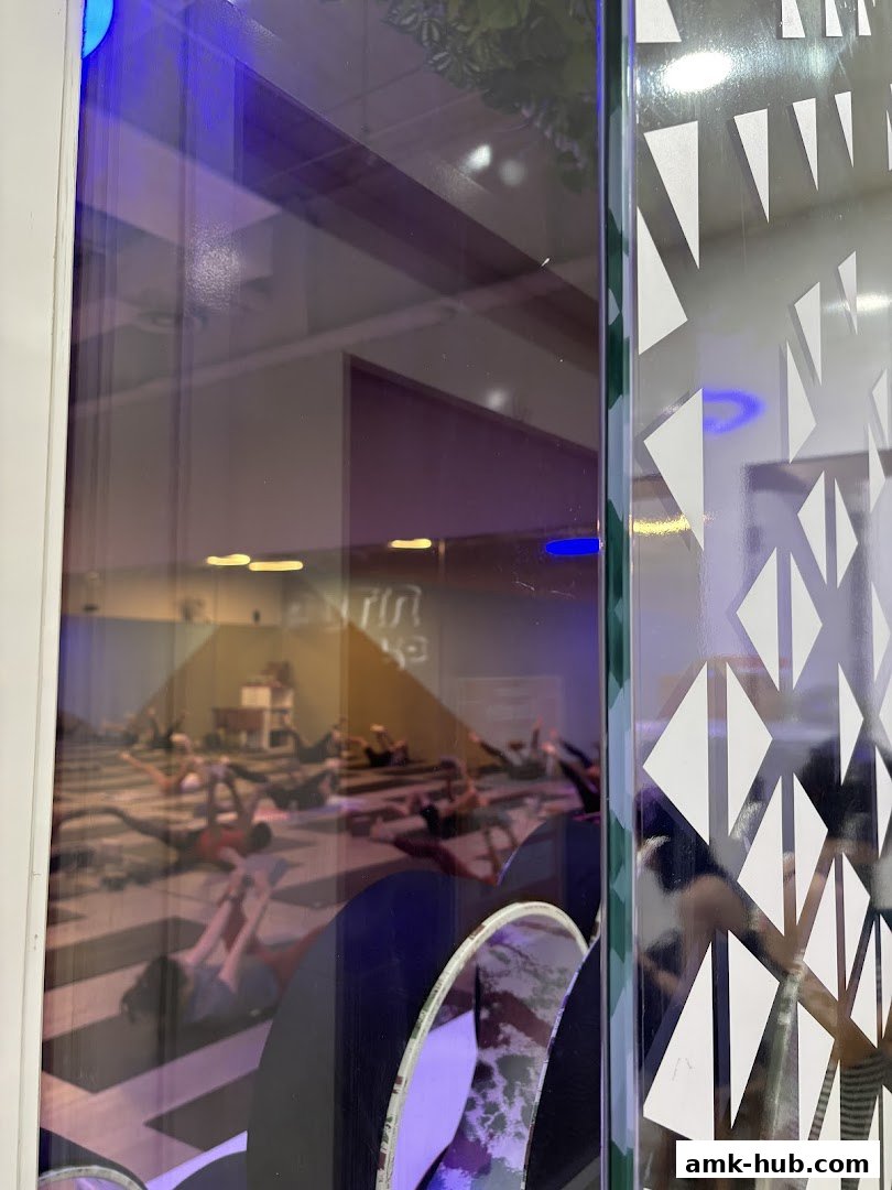 View of a yoga class in session through a shop window with decorative elements.