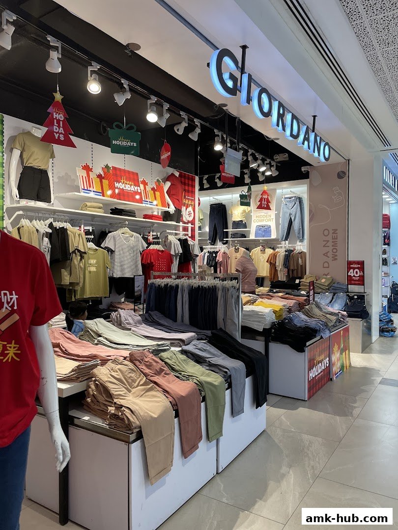 A well-lit clothing store interior showcasing a variety of casual wear, including pants and shirts, with holiday decorations.
