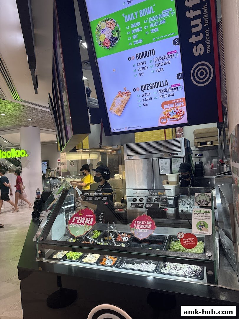 A food counter with a digital menu displaying bowls, burritos, and quesadillas.