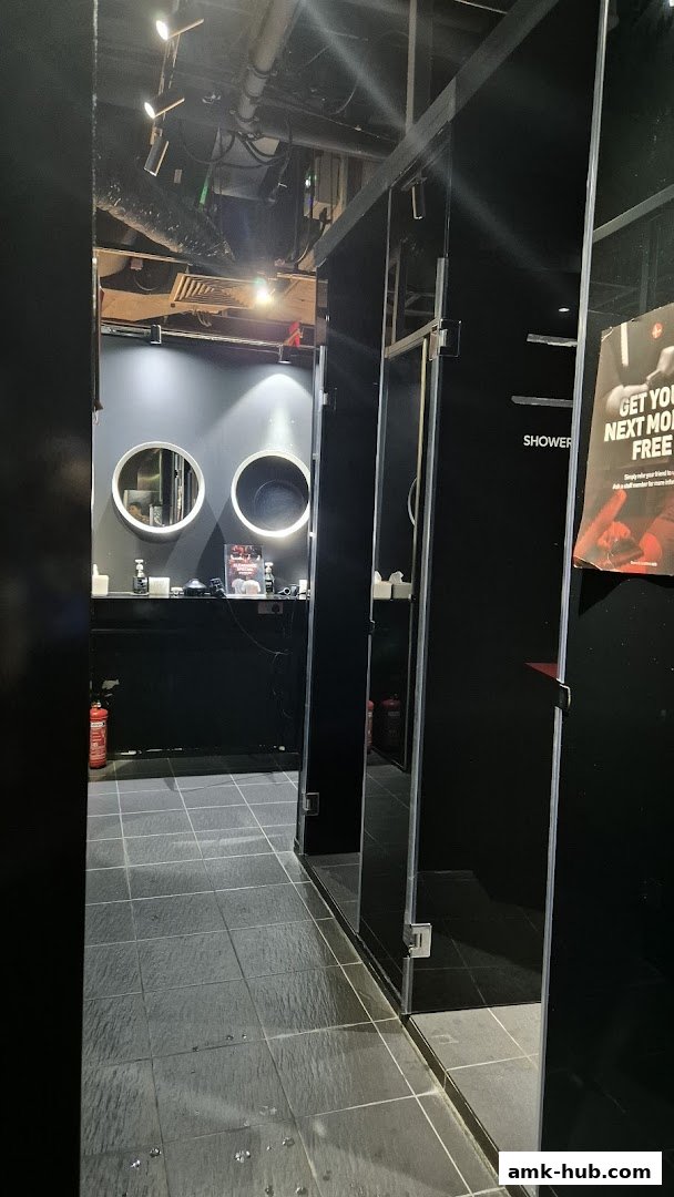 Interior view of a gym's changing room with shower stalls and a vanity area.