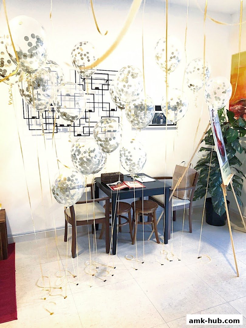 A room decorated with many clear balloons filled with confetti and gold ribbons.