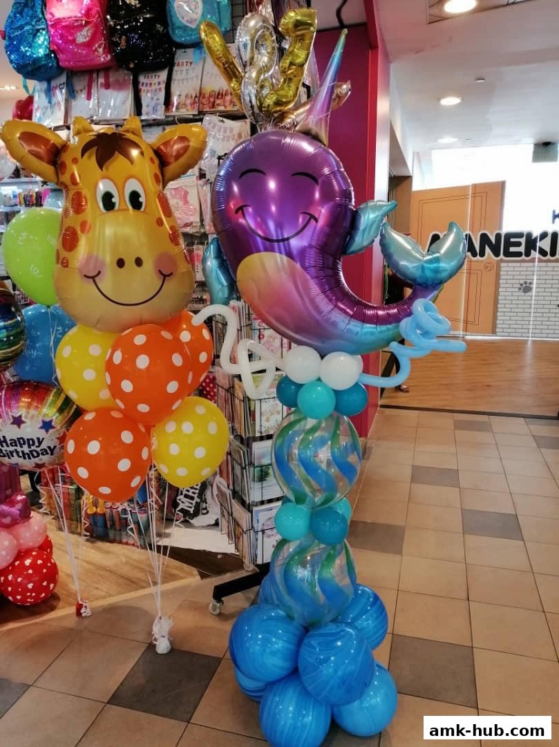 A colorful balloon display featuring a giraffe and a whale, with various party balloons in the background.