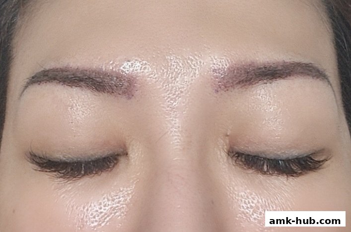 Close-up of a person's eyebrows and closed eyes, showing subtle cosmetic enhancements.