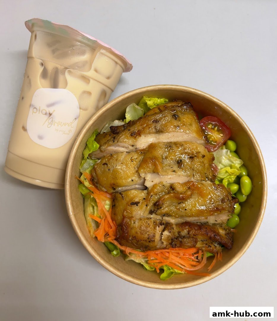 A bowl of salad with grilled chicken and a drink from Playground by PlayMade.