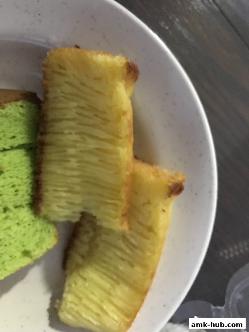 Close-up of layered yellow cake and green pandan cake slices on a white plate.