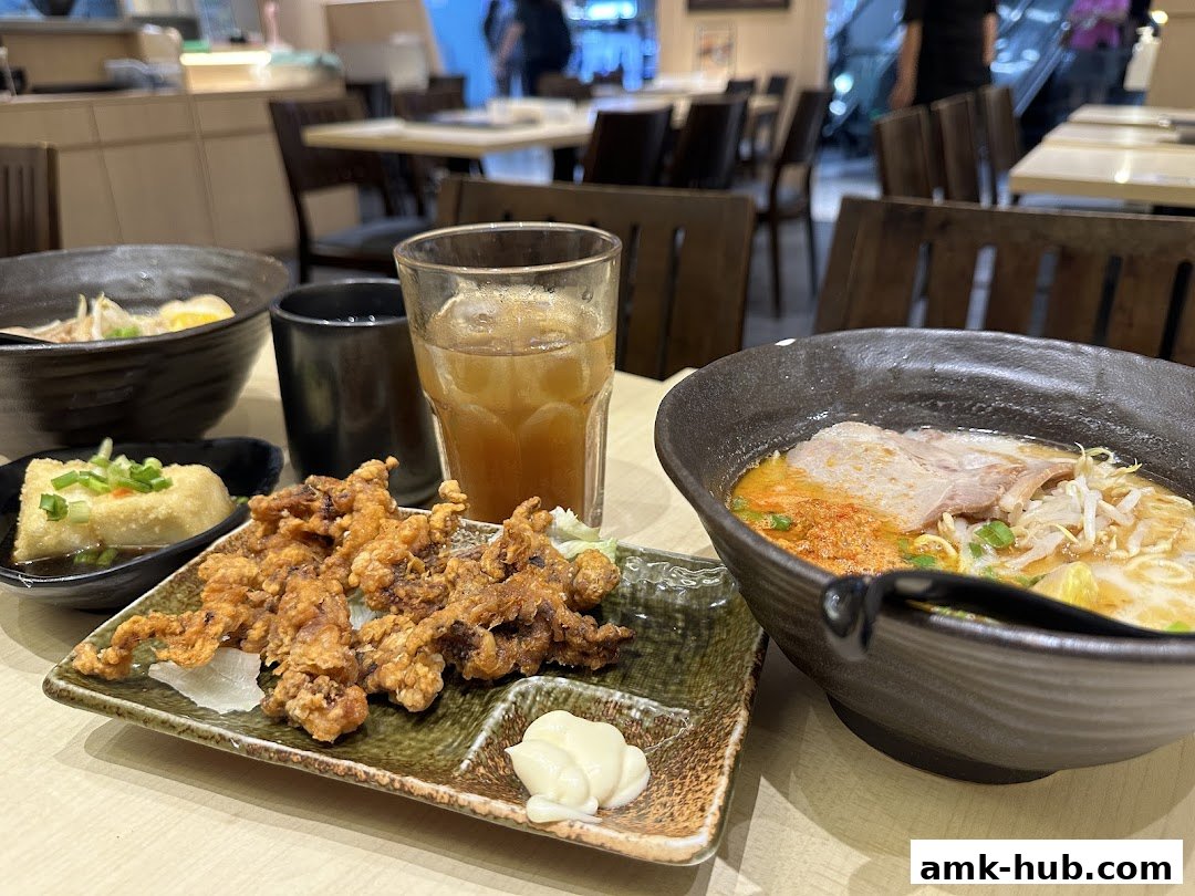 A table setting at Tokyo Shokudo with ramen, fried calamari, and a drink.