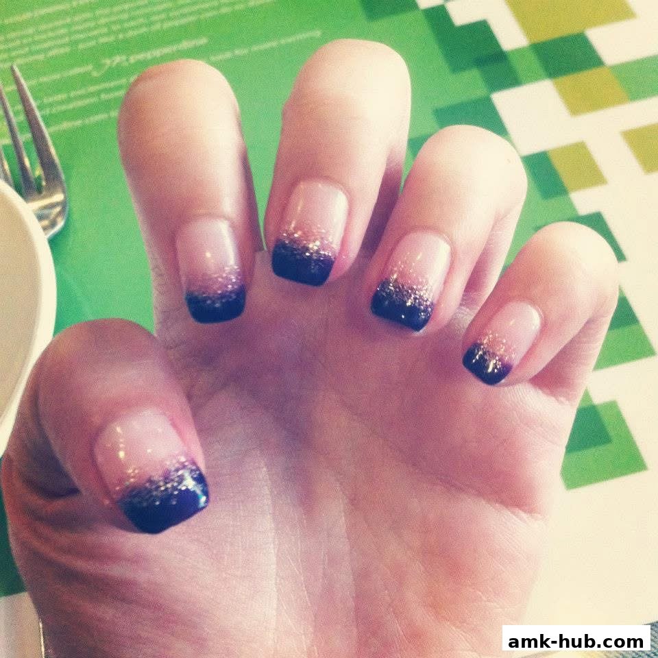 A hand with beautifully manicured nails featuring a French tip with glitter.