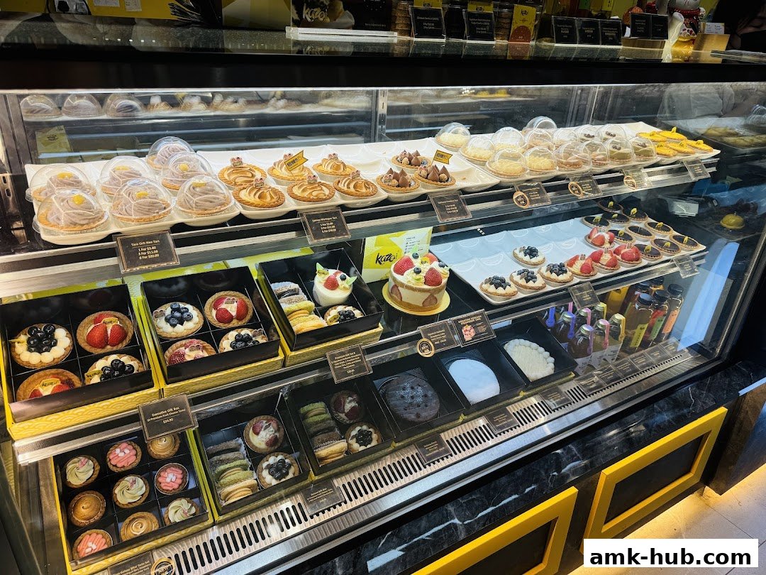 A display case filled with various beautifully decorated tarts, cakes, and pastries.