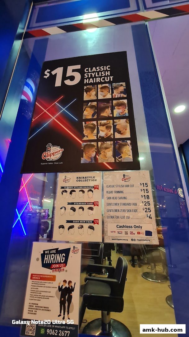 A barber shop window displaying prices for haircuts and a hiring advertisement.