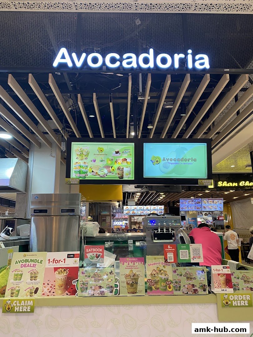 The Avocadoria shop front displays various promotions and menu items, with a neon sign above.