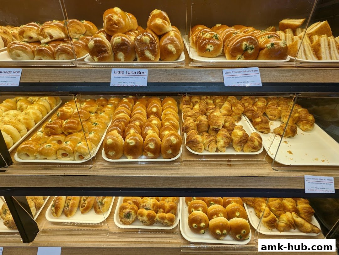 A display case filled with various freshly baked breads, buns, and sandwiches.