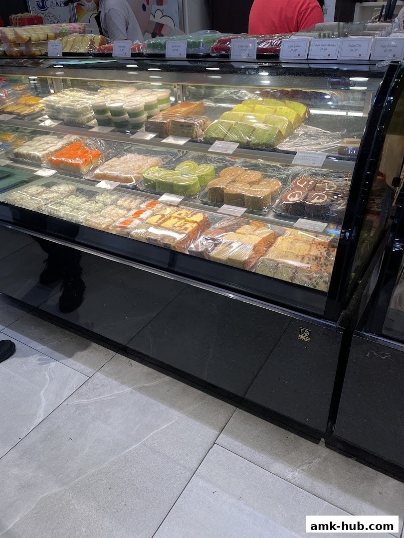 A display case filled with various colorful cakes and pastries, neatly packaged.