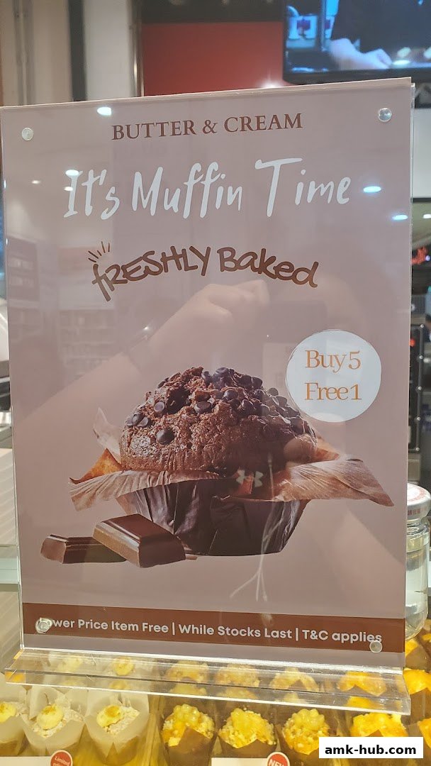 A sign advertising a 'Buy 5 Free 1' muffin deal at Butter & Cream bakery.