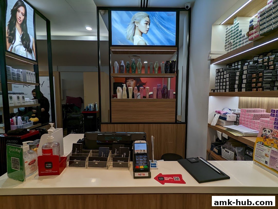 Interior view of a hair salon counter with products displayed on shelves and screens.