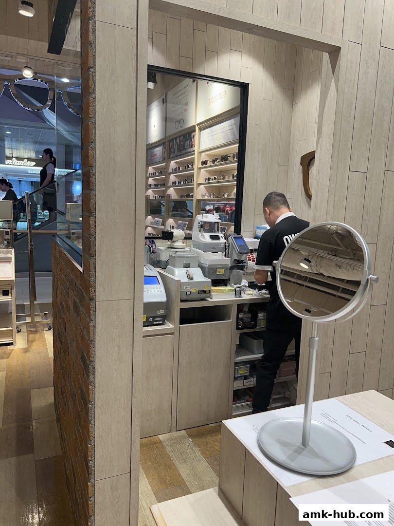 An optician's shop interior with a staff member behind the counter and shelves of glasses.