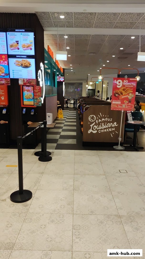 Interior view of Popeyes restaurant showing seating area, menu boards, and promotional displays.