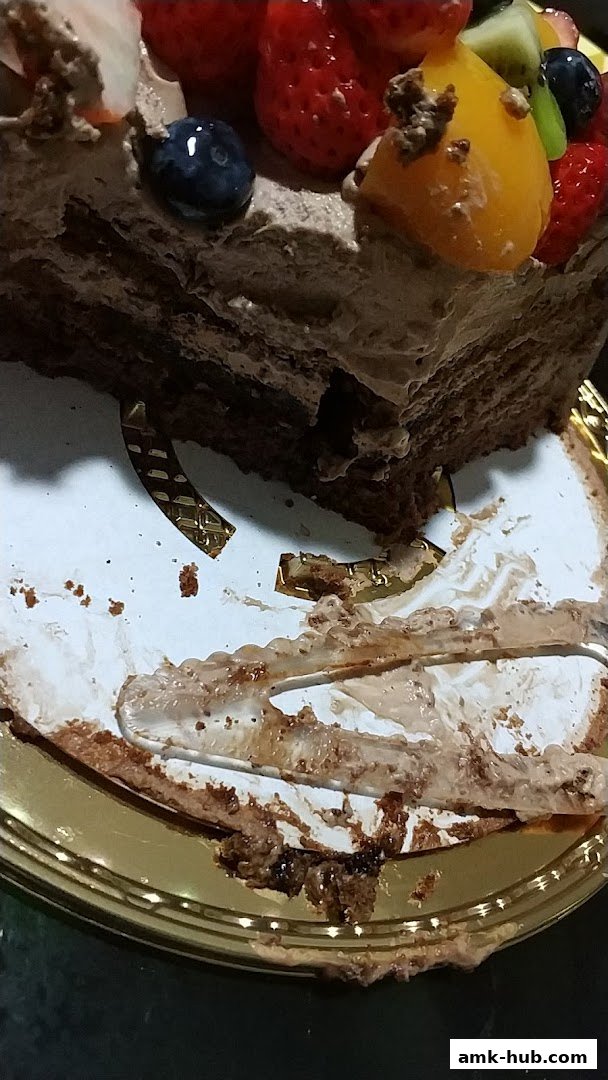 A slice of chocolate cake with fresh fruit toppings on a golden plate.