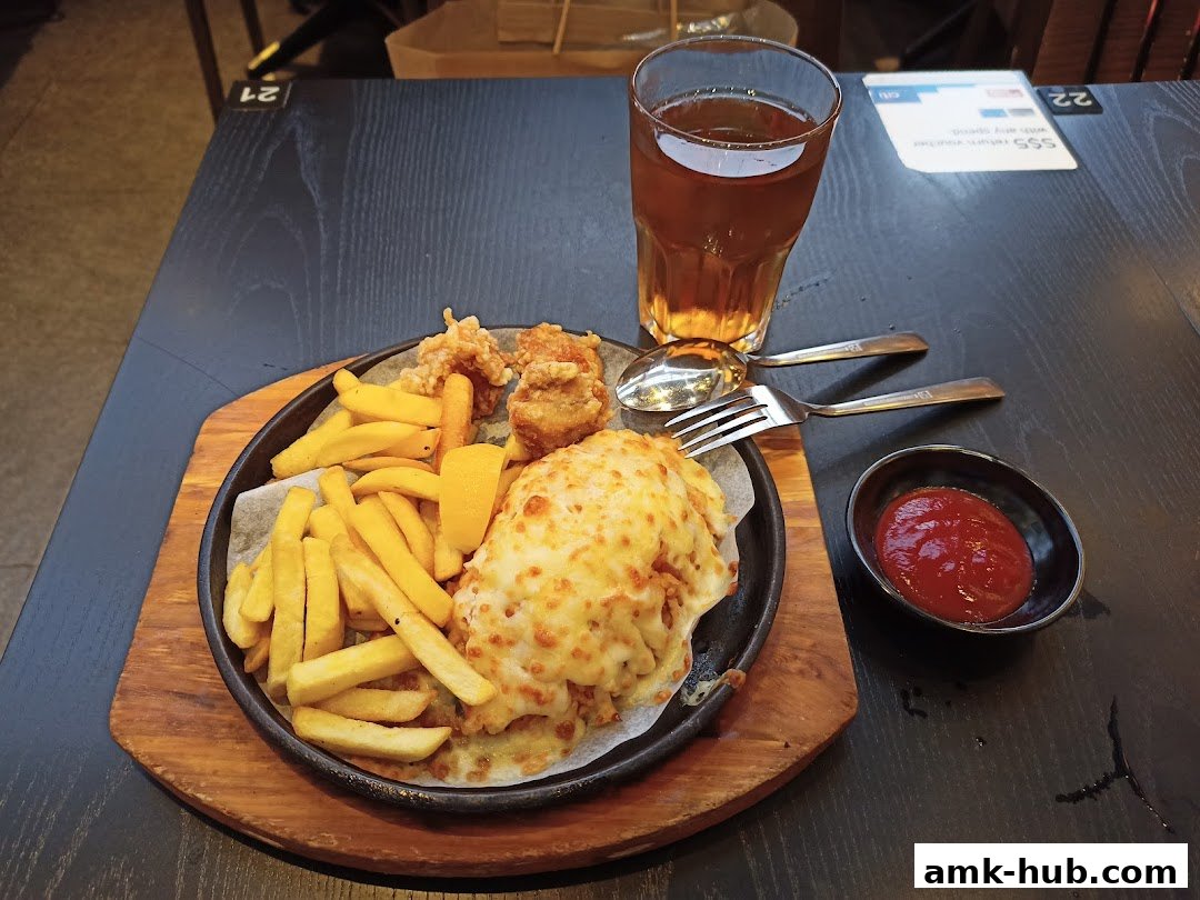 A sizzling platter of fried chicken, french fries, and a cheesy dish with a side of ketchup and iced tea.