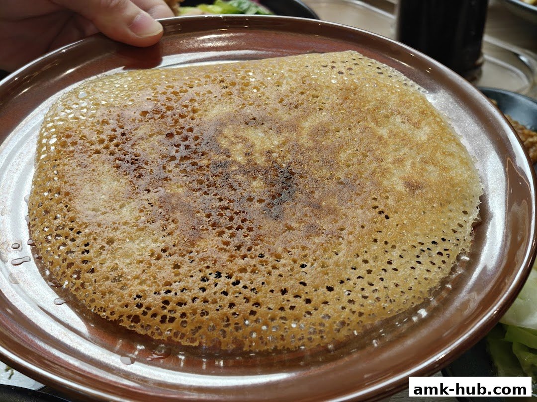 A close-up shot of a crispy, golden-brown pancake or crepe on a brown plate.