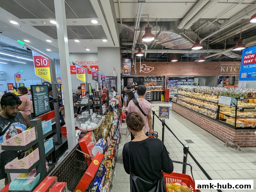 Customers queue at checkout counters in a well-stocked supermarket with a bakery section.