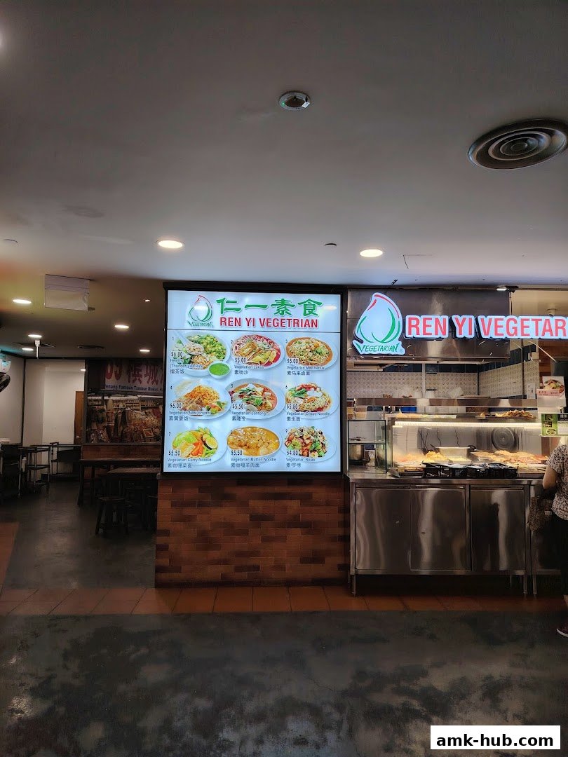 A brightly lit menu board displays various vegetarian dishes with prices.