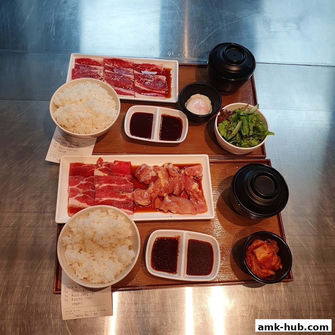 Two sets of Japanese BBQ meals with rice, meat, salad, and dipping sauces.