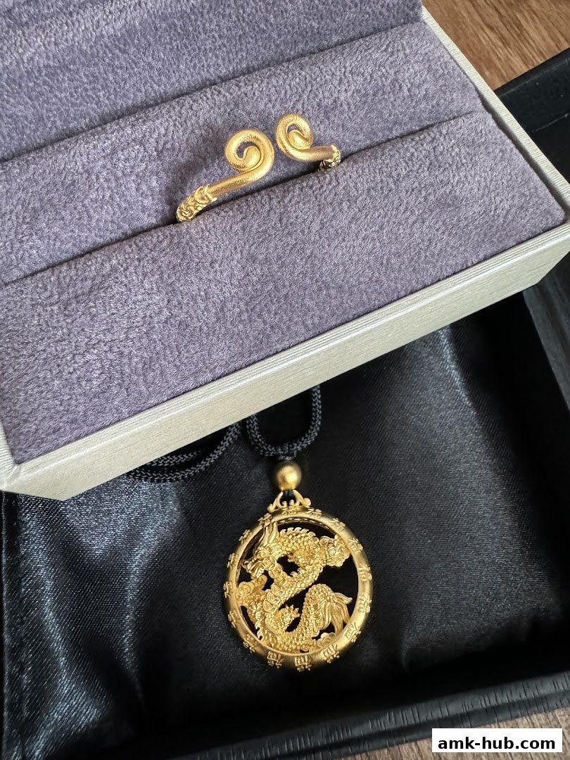 Gold jewelry, including a dragon pendant and a ring, displayed in a jewelry box.