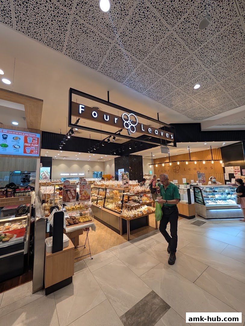 A bakery shop called Four Leaves with a display of various baked goods and customers.