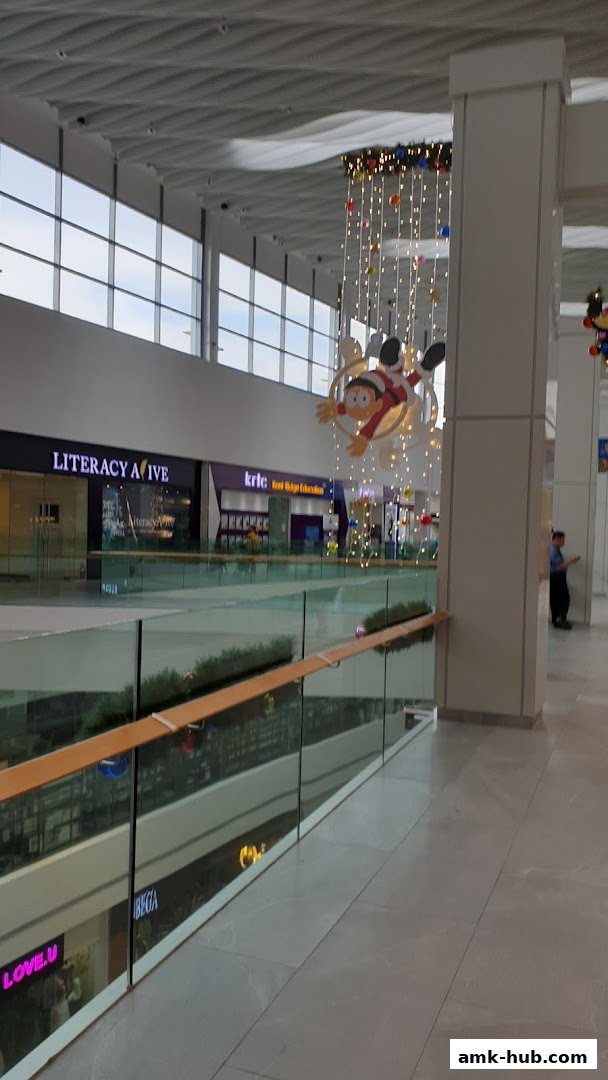 A view of a shopping mall interior with shops and decorative lights.