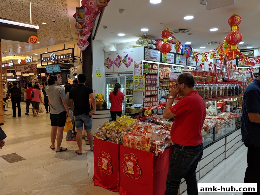 People browsing a retail store selling various food items and tonics, decorated for a festive occasion.
