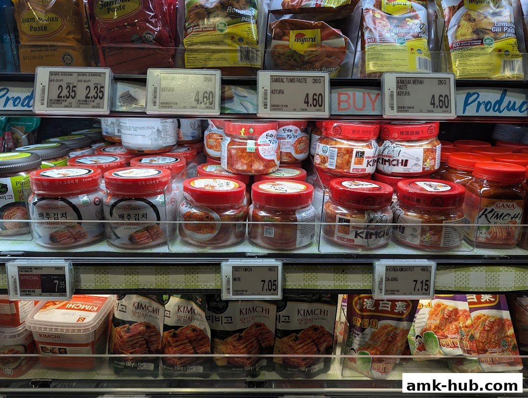A display of various kimchi and paste products in jars and packets on supermarket shelves.