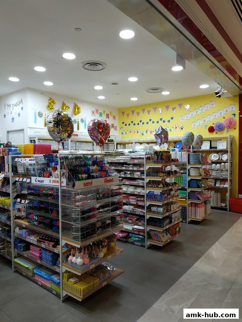 Interior view of a shop selling stationery, party supplies, and gifts, with colorful balloons and decorations.