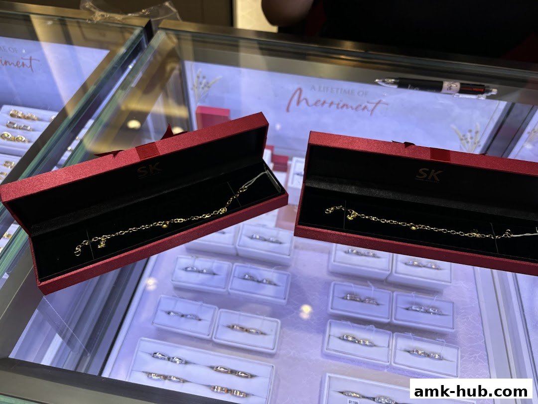 SK Jewellery displays elegant gold bracelets in red gift boxes, with rings showcased in display cases.