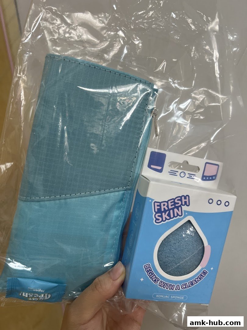 A hand holds a blue konjac sponge and a light blue pouch, both in plastic packaging.