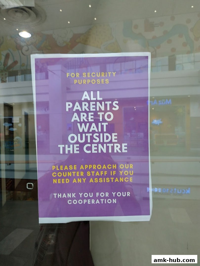 A sign on a glass door requests parents to wait outside the center for security purposes.