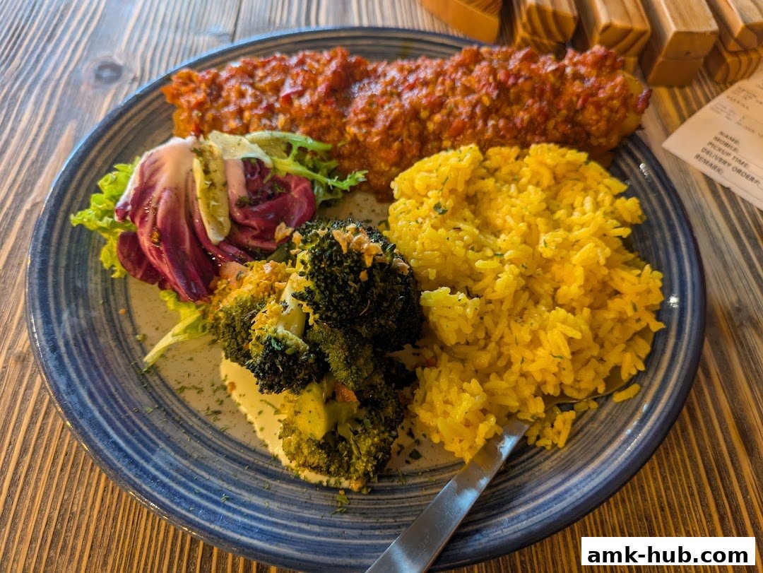 A plate of food with rice, broccoli, salad, and a meat dish.