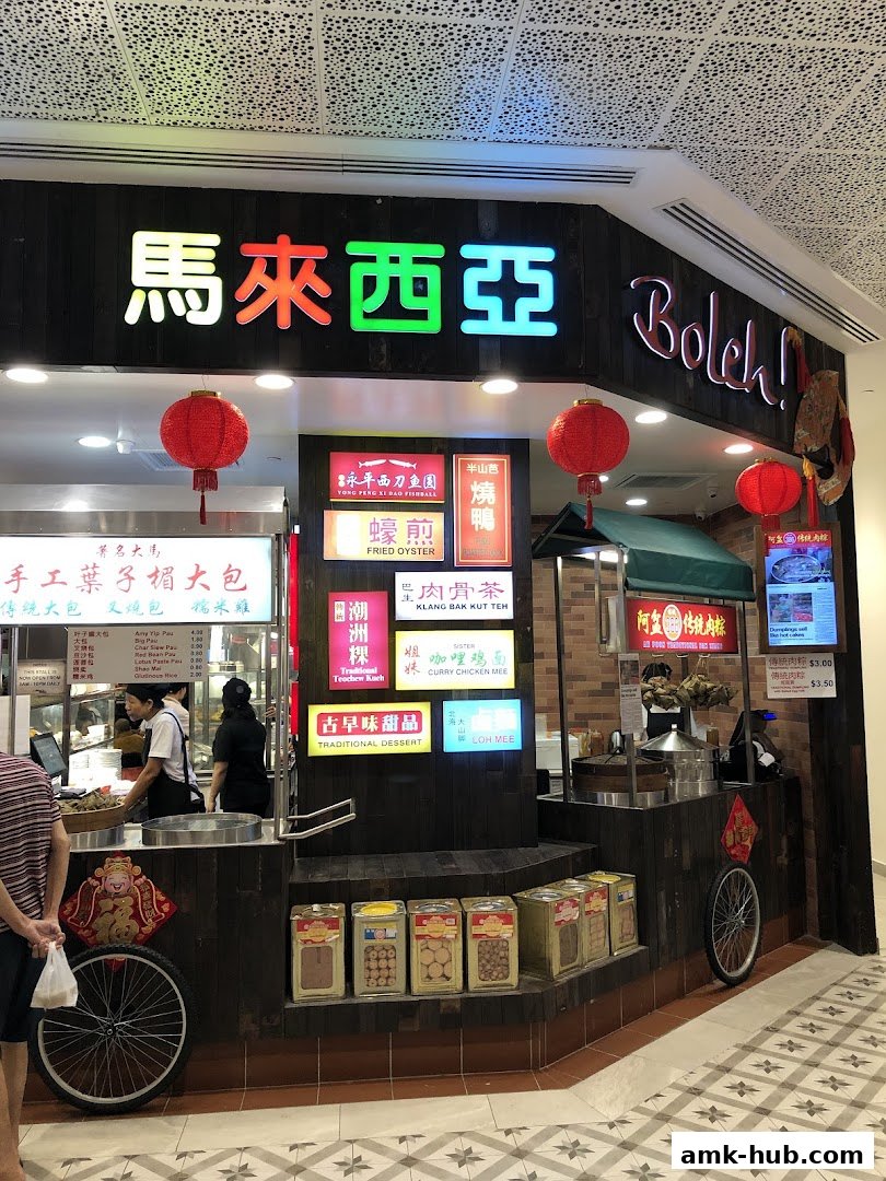 A Malaysian food stall with various dishes displayed and staff serving customers.