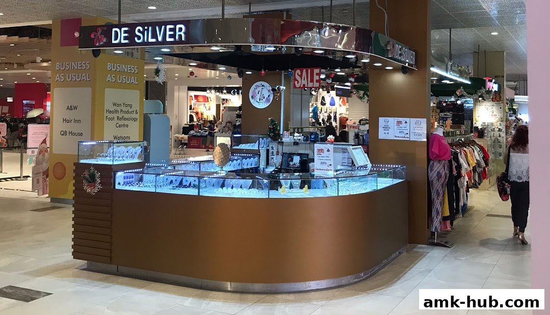A jewelry kiosk named De Silver with display cases filled with jewelry and a sale sign.