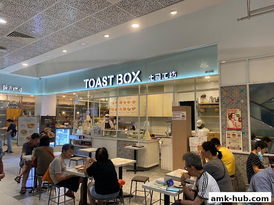 People dining at tables outside the Toast Box restaurant with its prominent signage.
